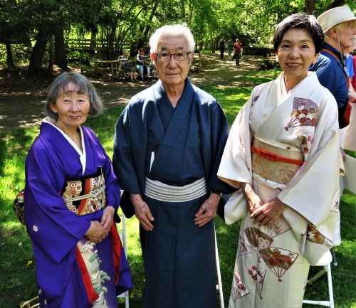 Three tea masters stand together in the Japanese garden